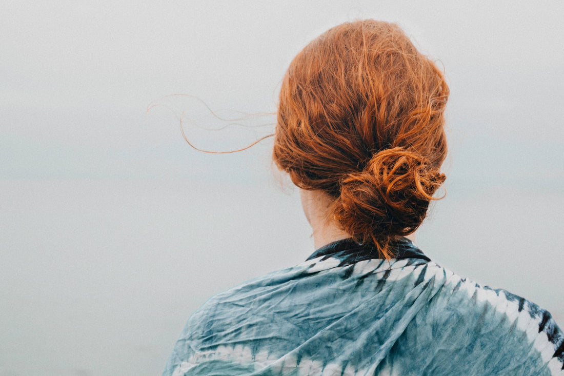 Mulher de costas, com cabelo ressecado preso com coque